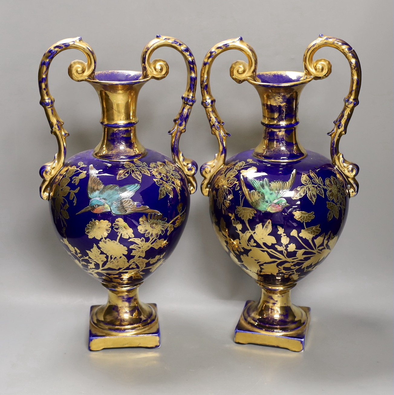 A pair of blue painted two-handled gilt pottery vases with birds amongst ornate gilt decoration. 41cm high